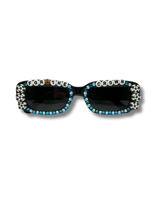 Black square sunglasses embellished with blue and white rhinestones, soccer beads, and white letter tiles spelling 'FOR THE CROWN' on a white background.