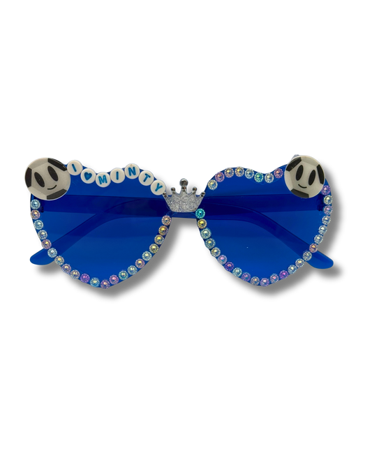 Blue heart-shaped sunglasses adorned with iridescent rhinestones, a silver crown at the bridge, and Sir Minty soccer ball head decorations on the top corners, shown on a white background.