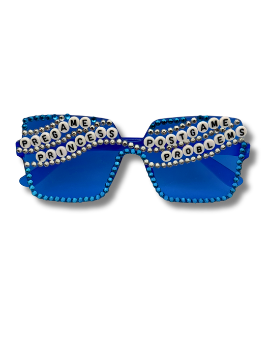 Blue rhinestone sunglasses with the words 'PREGAME PRINCESS' on one lens and 'POSTGAME PROBLEMS' on the other, shown on a white background.