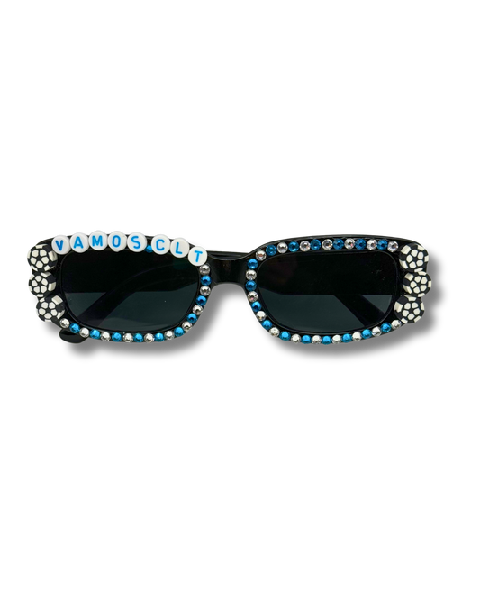 Black cat-eye sunglasses embellished with rhinestones and letter beads spelling 'VAMOS CLT' on the left frame, shown against a plain white background.